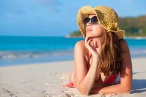 woman with hat laying on beach